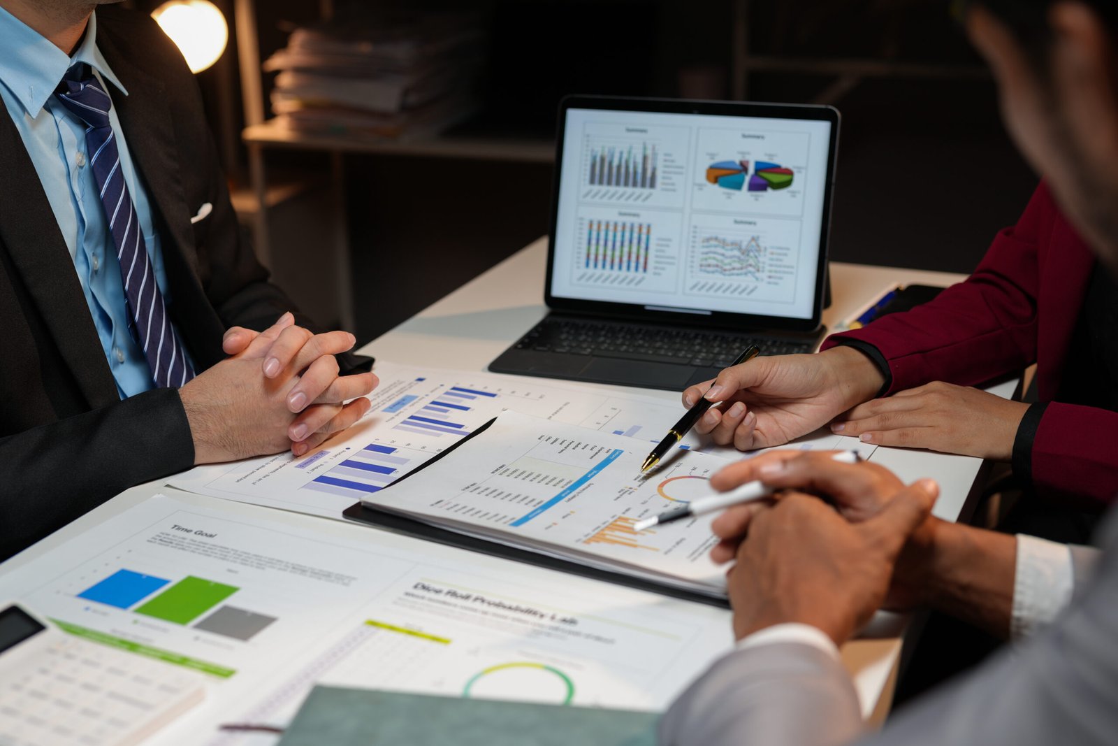 corporate professionals analyzing financial data late into the night, collaborating on a project and using a digital tablet for data analysis